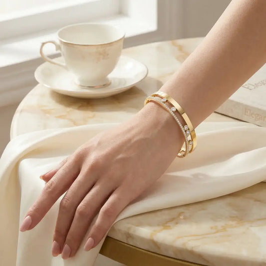 Elegant woman's wrist wearing the gold slider bangle bracelet on a marble table setting.