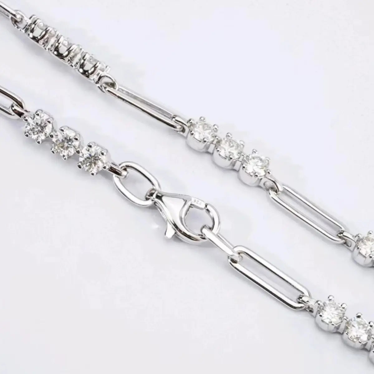 Close-up of the elongated paperclip links and moissanite stone setting on a neutral background.