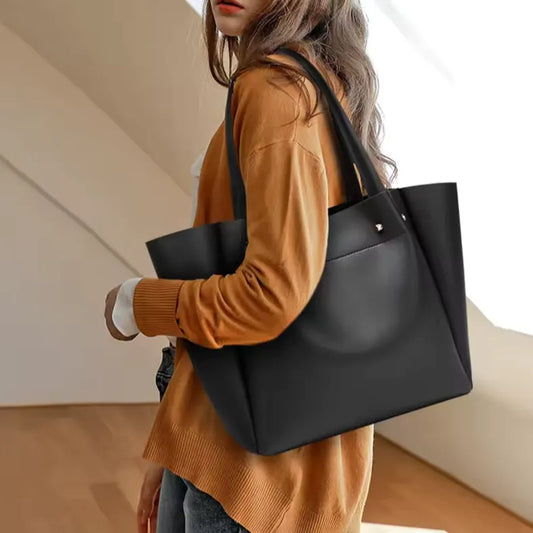 Model wearing a quiet-luxury leather handbag, styled in a minimalist day-to-night look with refined feminine elegance.