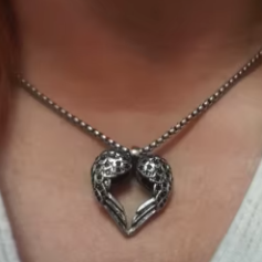 Sterling silver winged heart charm on model’s hand