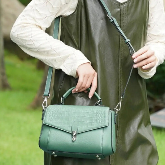model wearing green alligator-embossed leather satchel crossbody