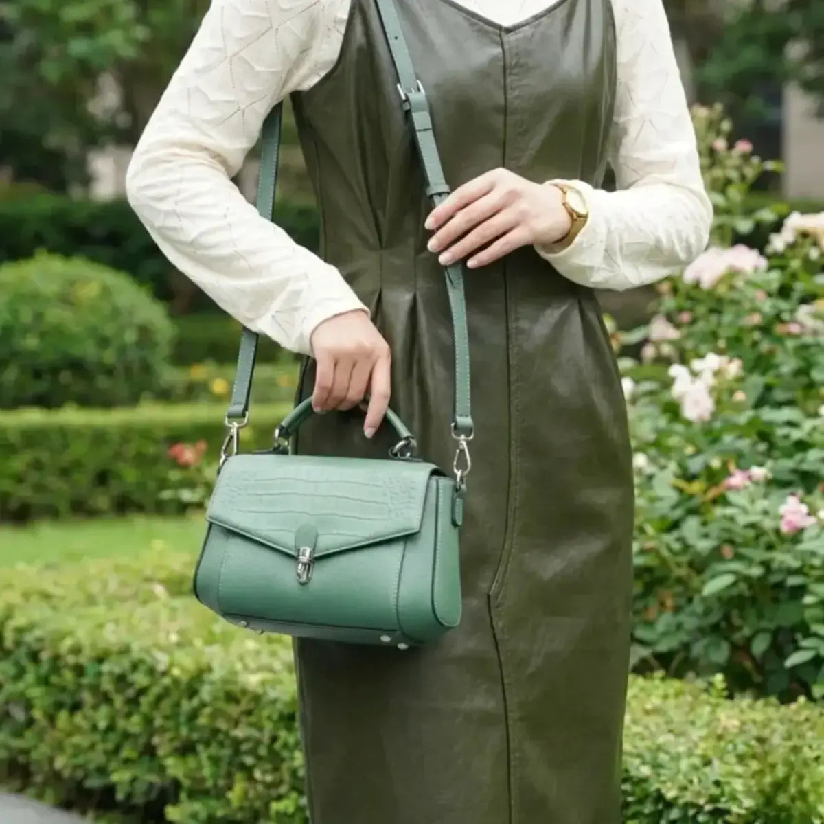 Elegant emerald green leather bag worn as a crossbody for a modern professional look.