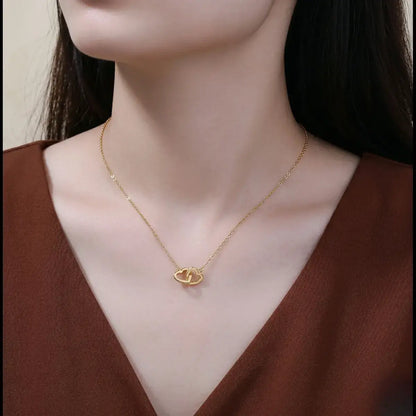 Close-up of a sophisticated model with a classic updo wearing a minimalist double-heart gold necklace in a rich gold colour.