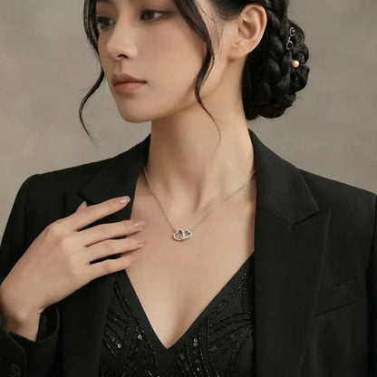 Elegant woman wearing the Moissanite Interlocking Heart Necklace in 925 silver paired with a sophisticated black blazer.