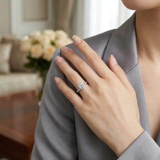 A 925 sterling silver V-shape (chevron) ring set with delicate stones and a central brilliant-cut moissanite, worn by a model in a grey tailored blazer.