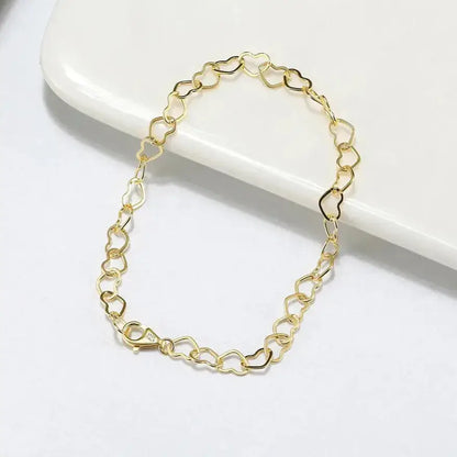 close-up of polished gold heart links with lobster clasp