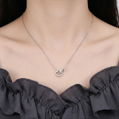 Close-up of a model wearing the silver Moissanite Interlocking Heart Necklace, highlighting the delicate scale and brilliant sparkle.