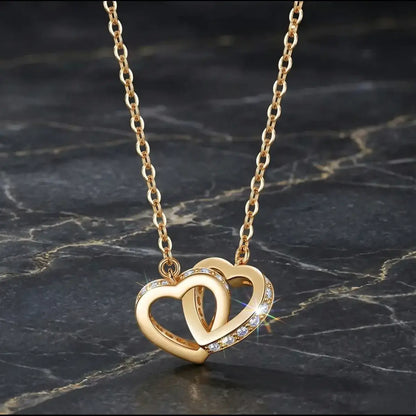 Macro shot of twin interlocked hearts in yellow gold, showcasing the intricate pavé jewellery craft with moissanite stones on the side.