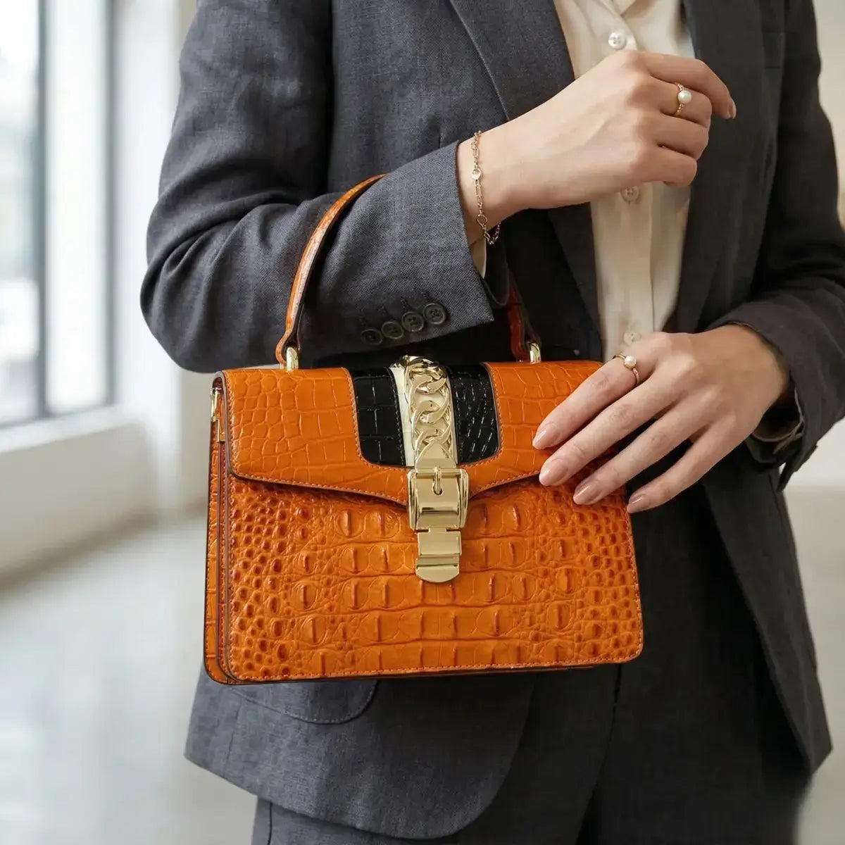 Close-up of the Orange Leather Crossbody Handbag in use, showcasing the croc-embossed leather texture and the gold-tone metal clasp with chain.