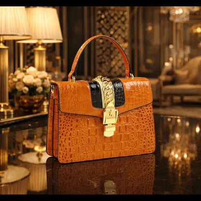 Structured Orange Croc-Embossed Leather Handbag with prominent gold-tone chain and clasp detail, in a luxury setting.