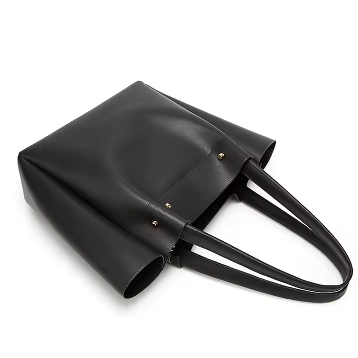 Elegant minimalist black tote bag worn over shoulder by woman