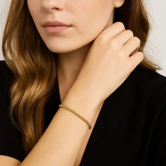 woman wearing gold beaded bracelet